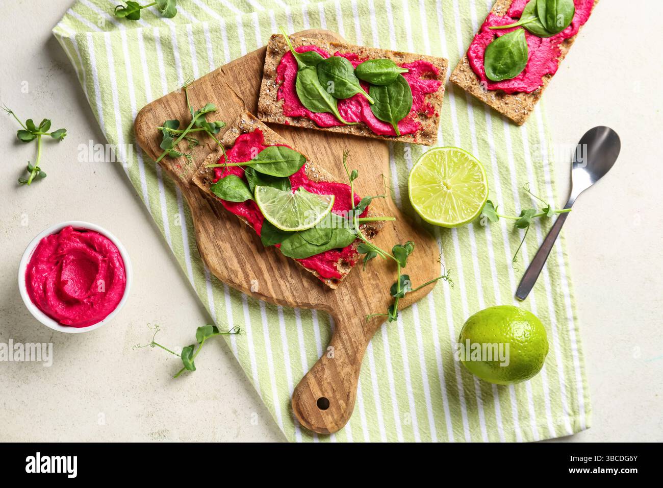 Composition with crispbreads, tasty beetroot hummus and basil on light background Stock Photo