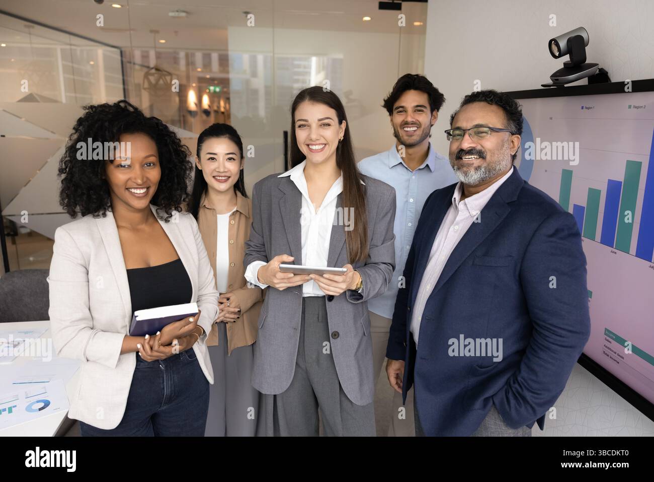 Diverse group of five businesspeople stands in modern conference room Stock Photo