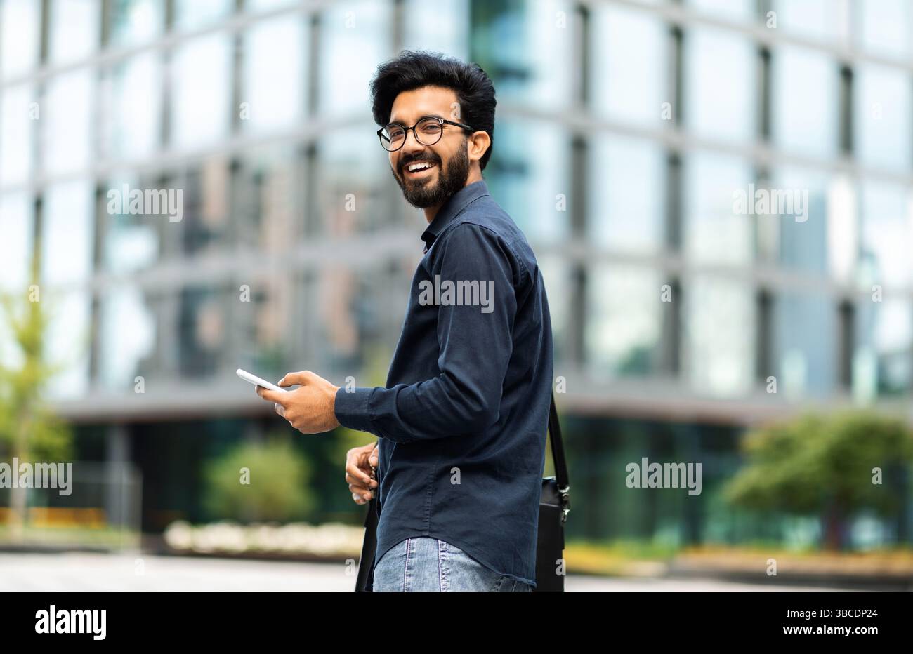 Happy middle eastern IT professional going to office, using phone Stock Photo