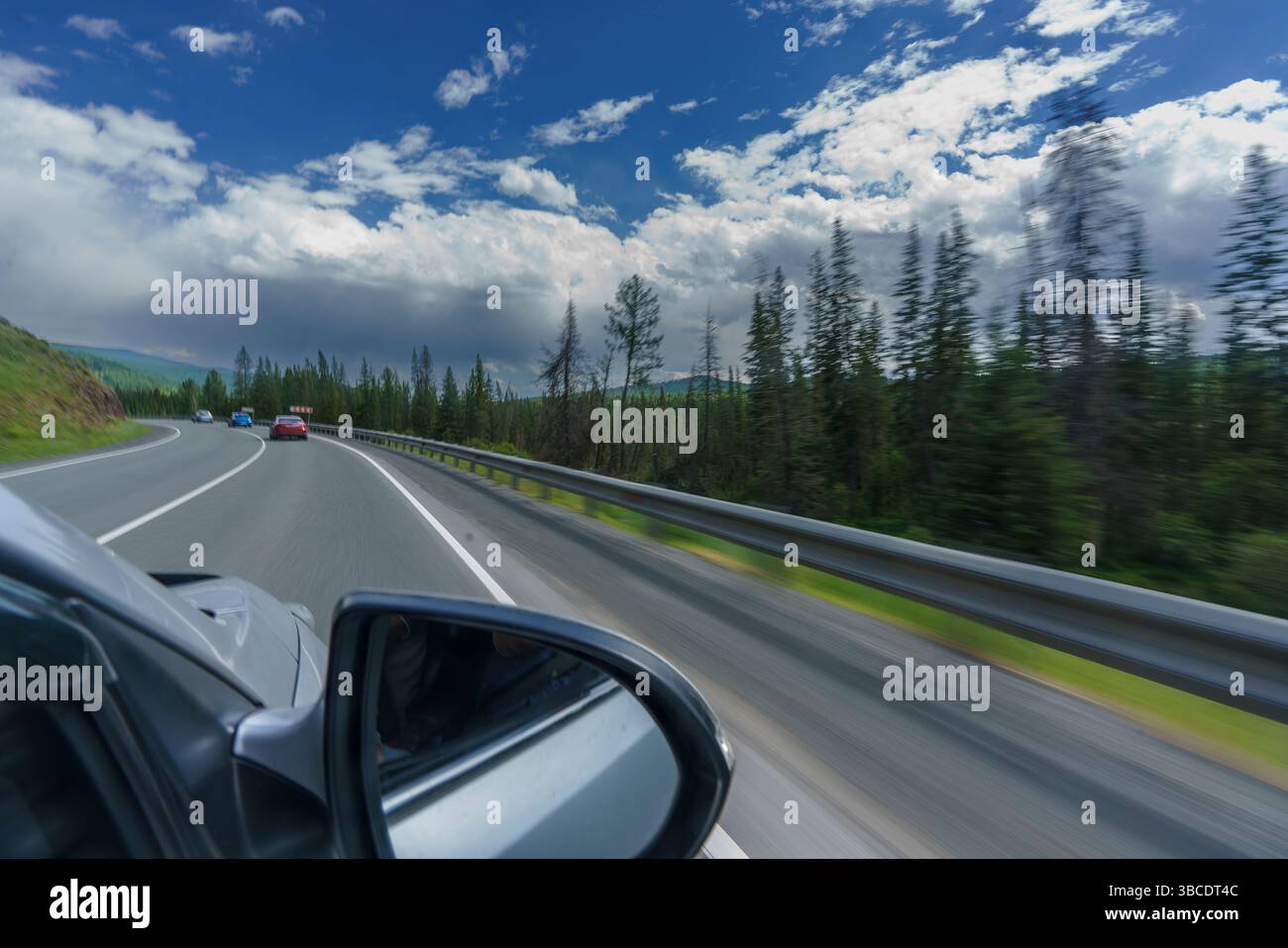 a feelings of speed due to smeared roadsides and nature when driving fast on a highway with a blue sky Stock Photo