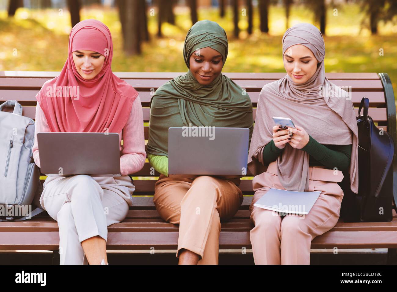Arab Ladies Using Smartphone And Computers Learning Online In Park Stock Photo