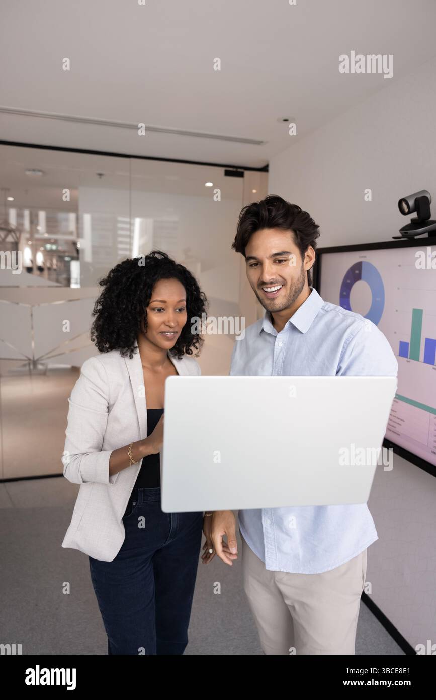 Two multiethnic young 30s professional teammates working together using laptop Stock Photo