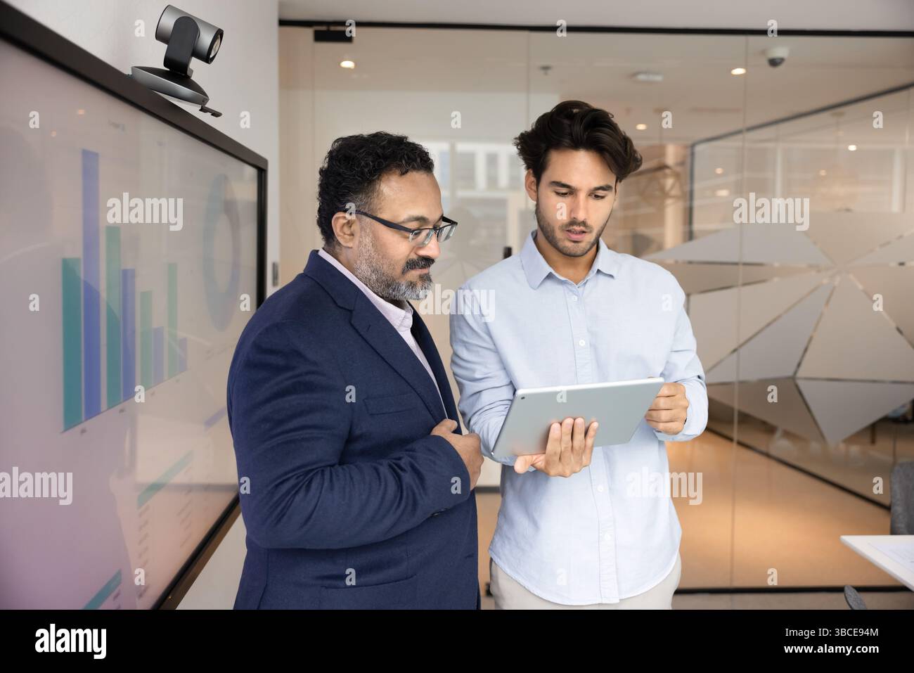 Two focused businessmen analyzing performance metrics displayed on tablet Stock Photo