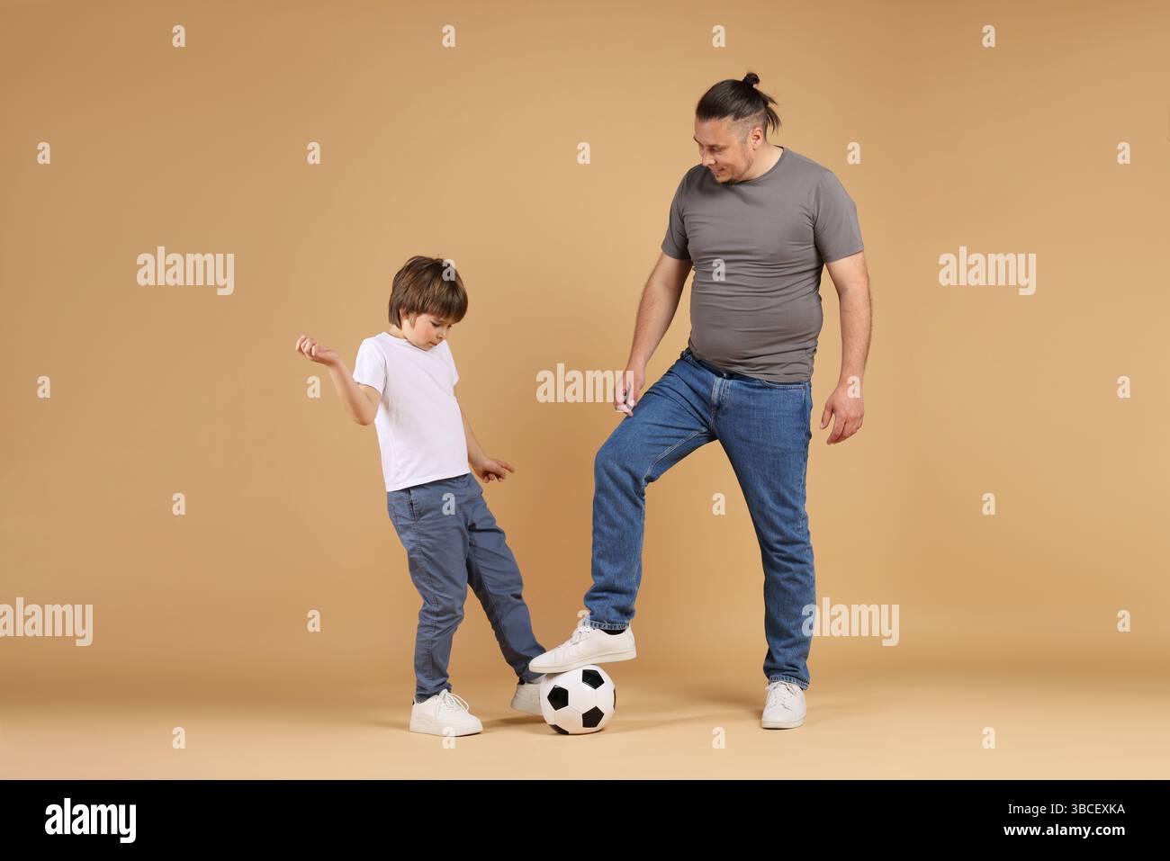 Father and his son playing football on beige background Stock Photo - Alamy