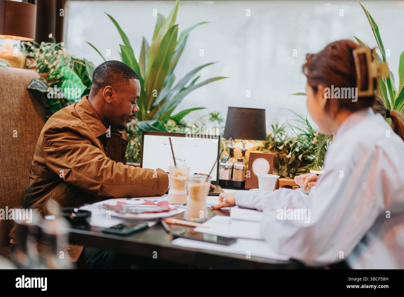 Collaborative brainstorming session between colleagues in a modern cafe setting Stock Photo