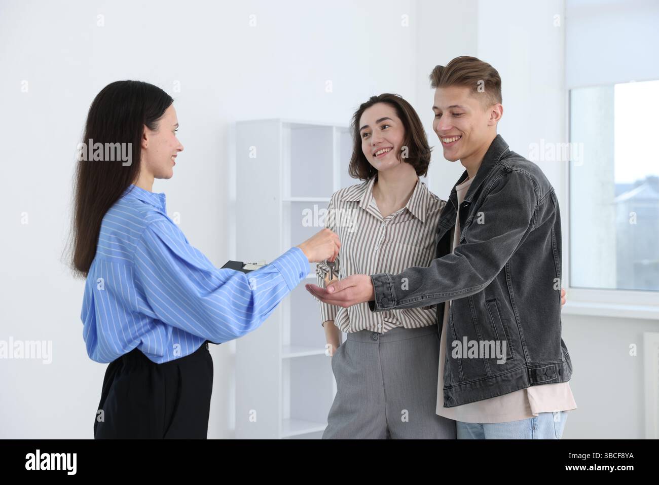 Real estate agent giving house key to new owners indoors Stock Photo ...