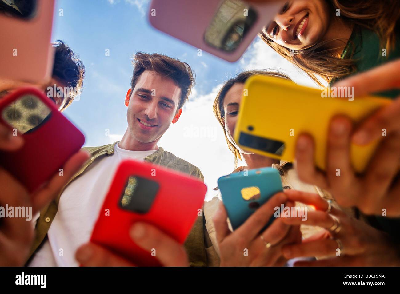 Group of young people using mobile phones together outdoors Stock Photo