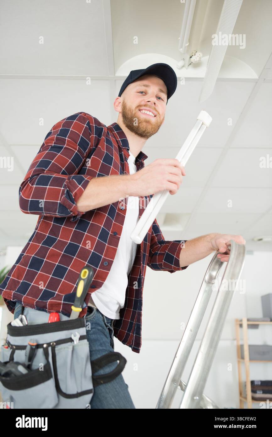 happy electrician man worker installing ceiling fluorescent lamp Stock ...