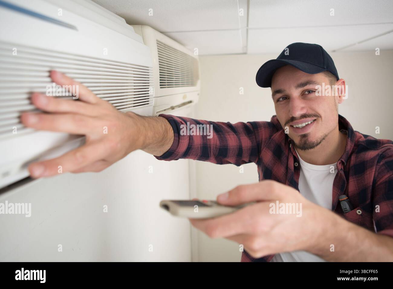 technician testing air conditioning unit with remote control Stock Photo