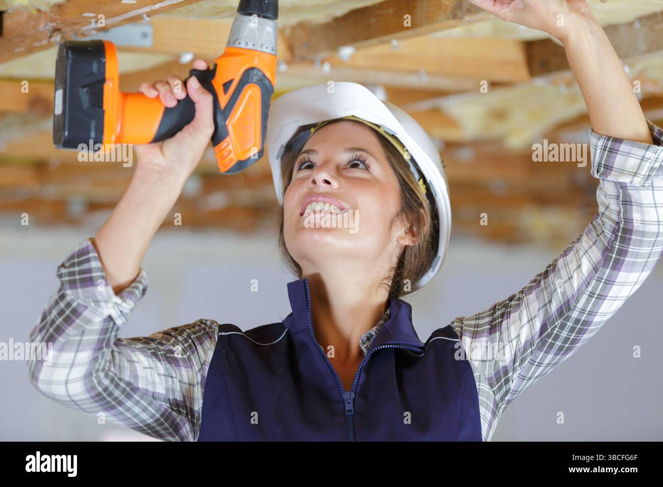 female construction worker using cordless drill Stock Photo