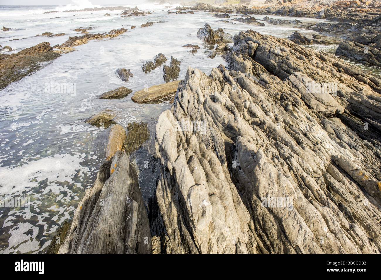 Elongate Rocks Sedimentary rocks stretch out towards the ocean at Storms River Mouth ...