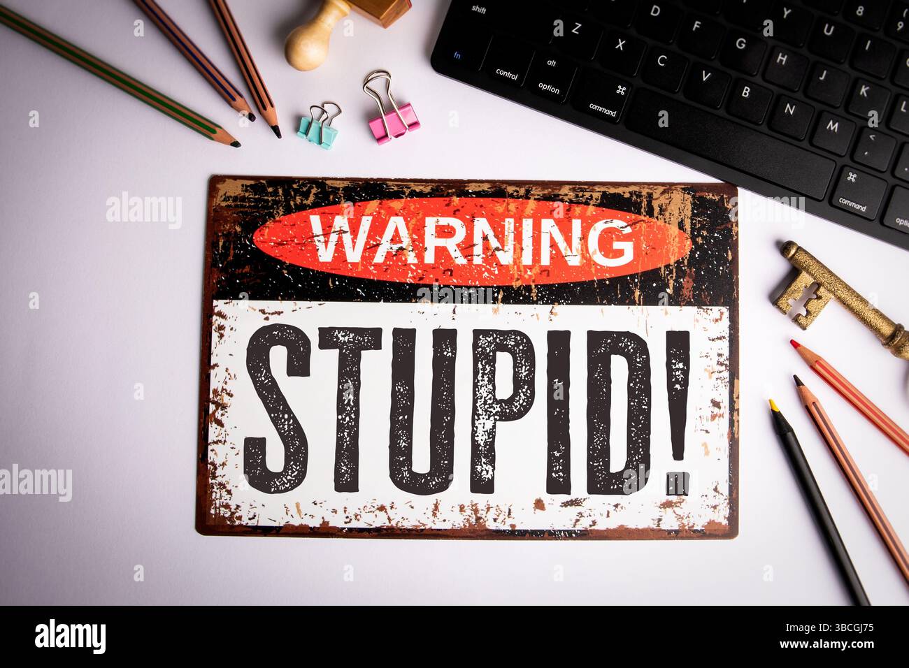 Stupid Warning Sign On Desk With Keyboard Pencils And Stationery