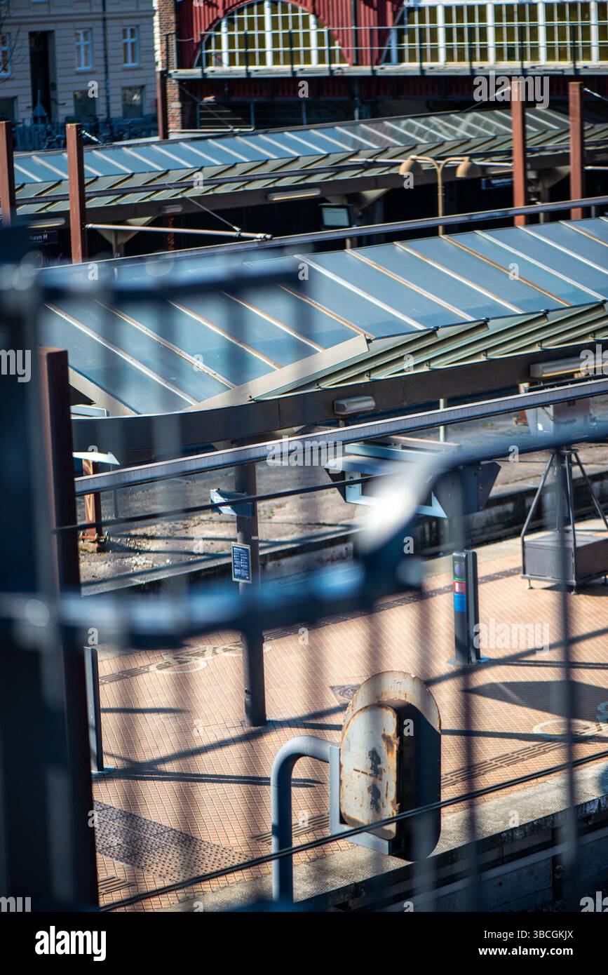 A realistic and moody photo capturing a train station partially obscured by iron or steel fences. Stock Photo