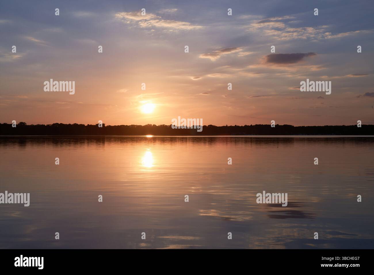 Serene sunset over a calm lake reflecting the colorful sky. Mecklenburg Lake Plateau, Germany Stock Photo