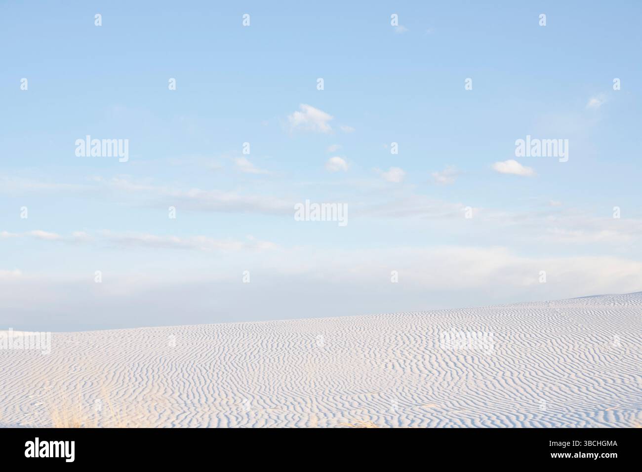 Vast desert landscape with rippled sand dunes under a clear blue sky ...