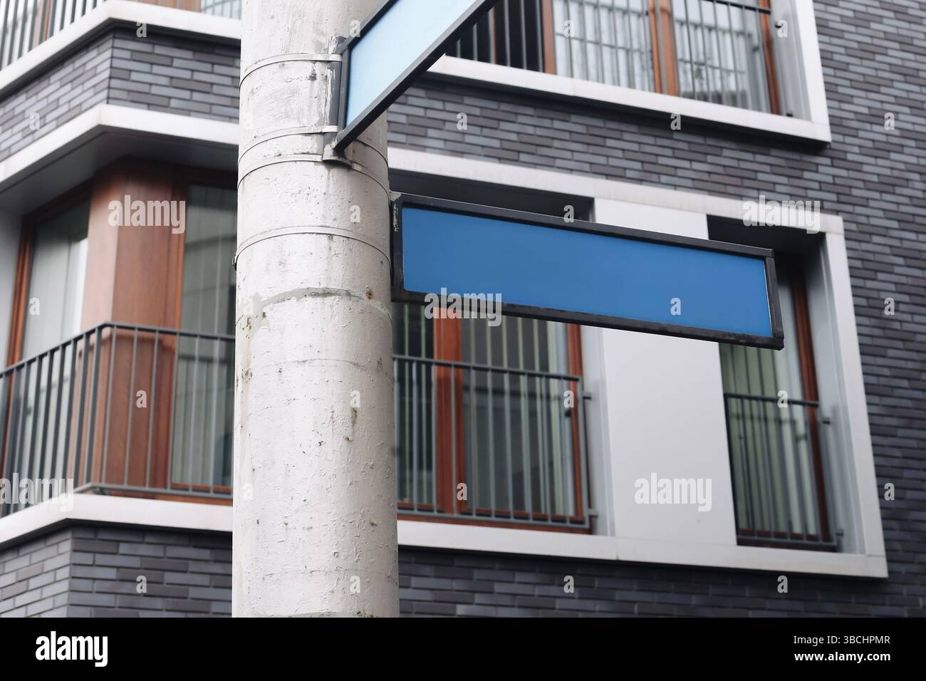 Empty street signs in city. Blank blue arrows on pole. Urban road direction indicators. Modern architecture background. Navigation concept. Copy space Stock Photo