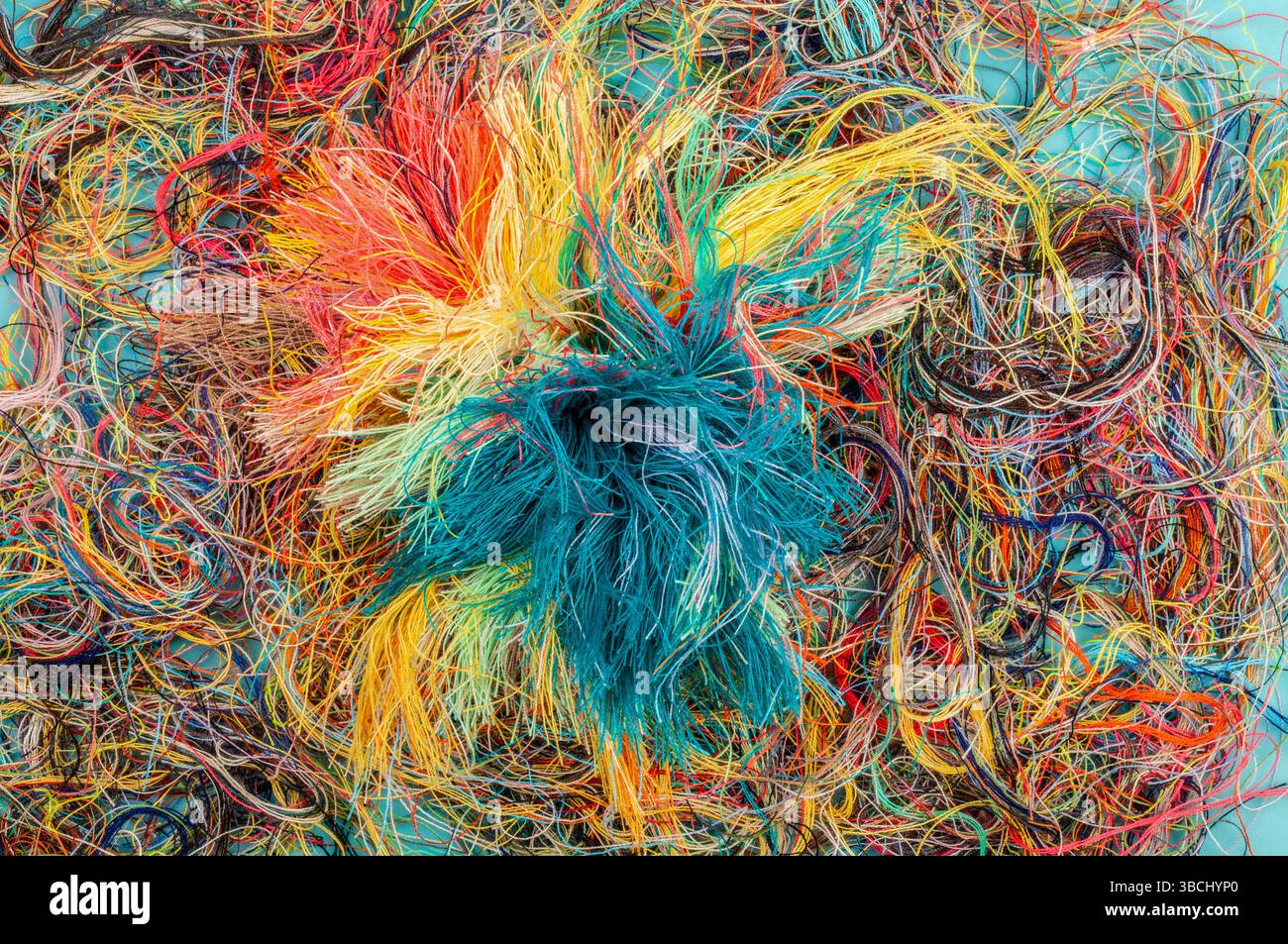 Colorful tangled threads on blue background. Closeup. Stock Photo