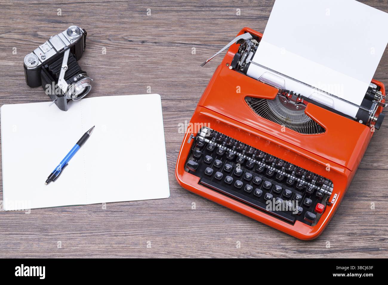 Analogue camera, notebook, pen and typewriter on a wooden table Stock Photo