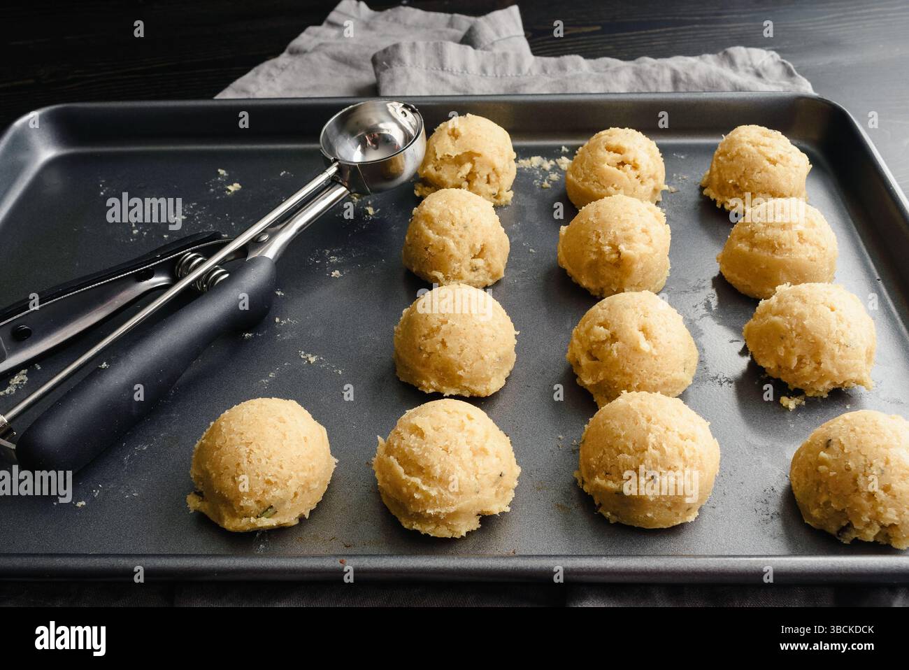 Scoops of Sugar Cookie Dough on a Sheet Pan: Non-stick baking pan with balls of cookie dough and a cookie scoop Stock Photo