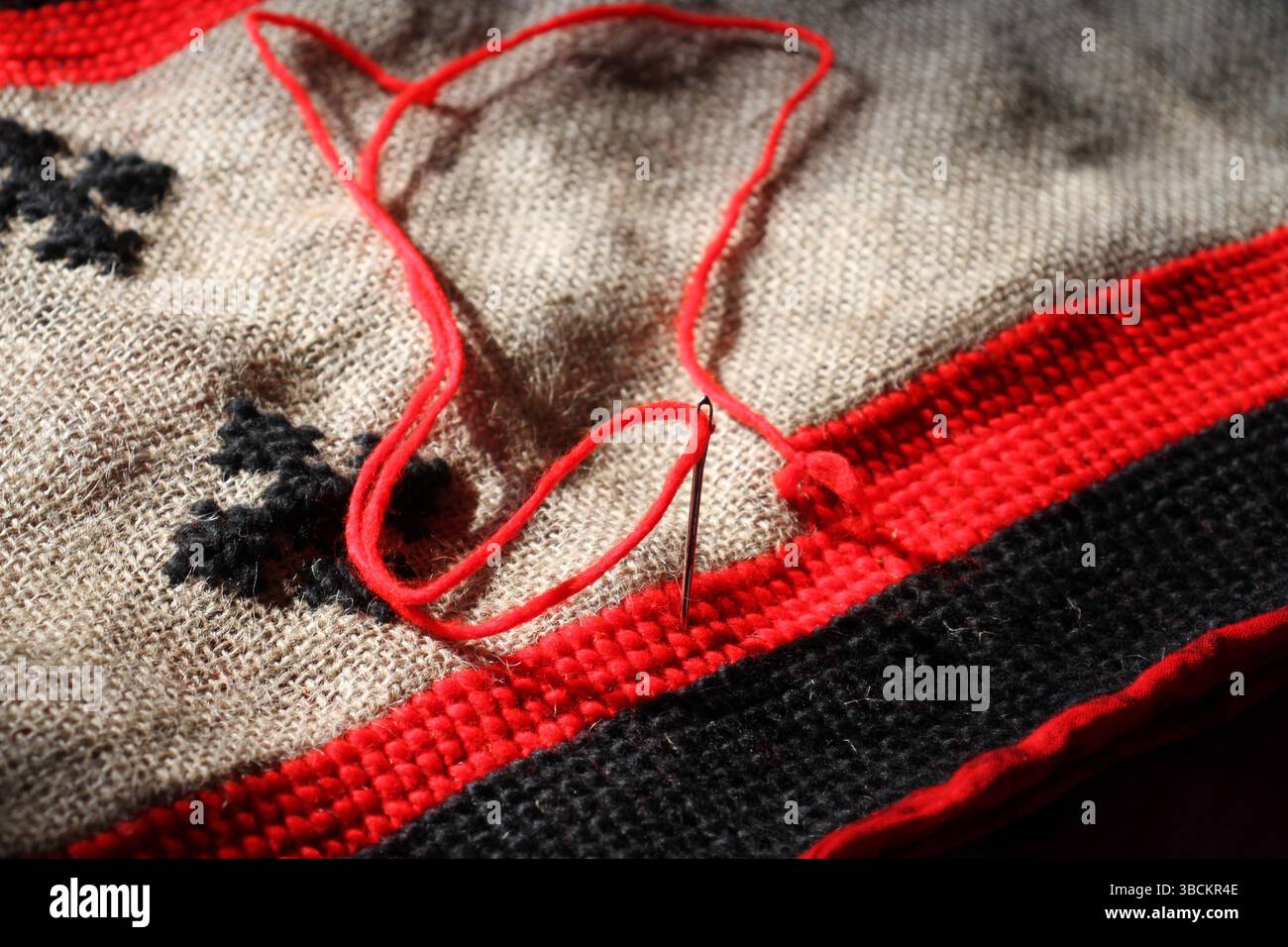 A red and black colored threads are using to make a handmade mat, the mat is in making process. Stock Photo