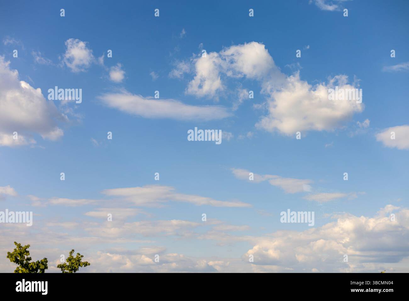 Fluffy white clouds drift across an expansive blue sky during a ...