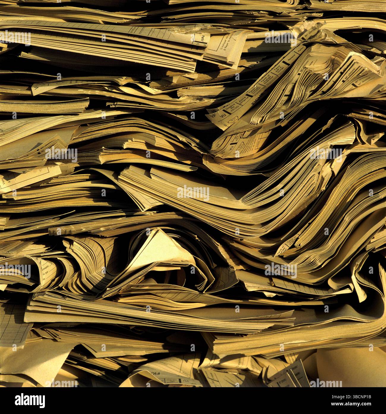 A large compressed pile of paper products is stacked at a recycling ...
