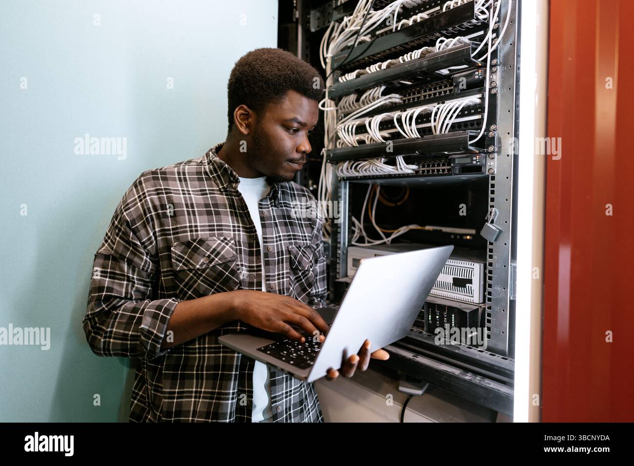 Technician configuring server settings in a data center during the day Stock Photo