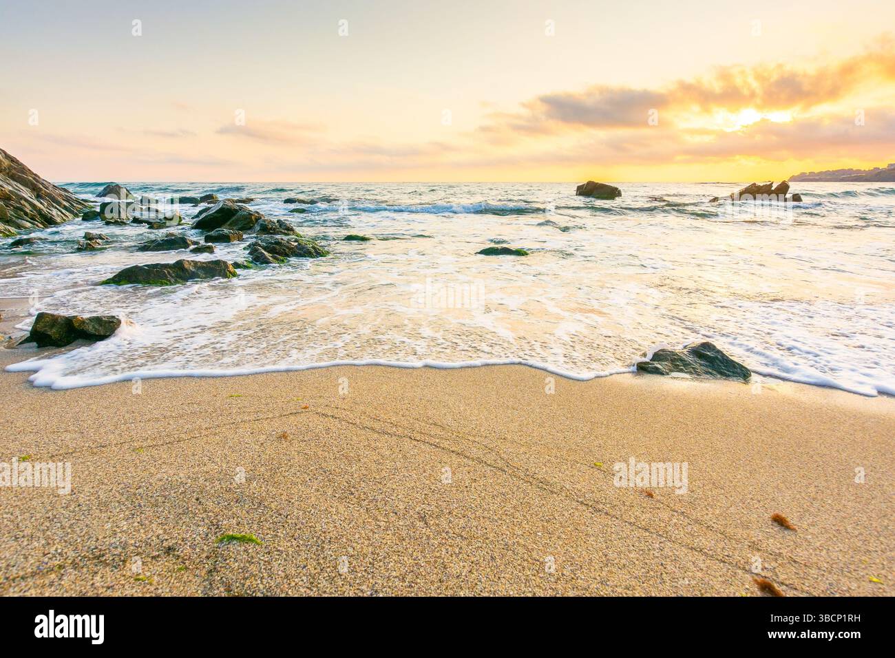 summer holiday season at the seaside. beautiful seascape at sunrise. golden sandy beach in morning light. sun behind fluffy clouds on sky above horizo Stock Photo