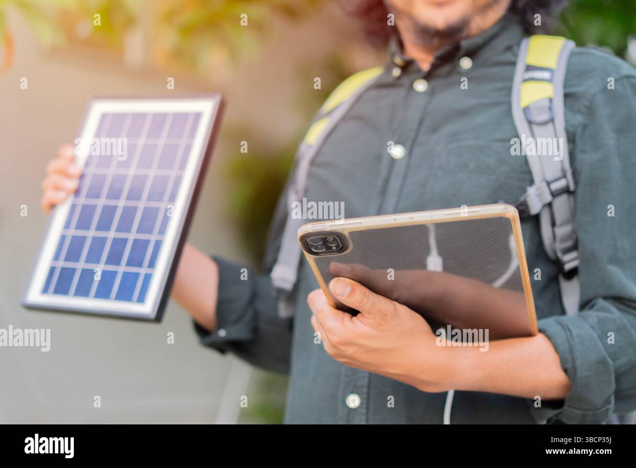 Engineer using portable solar panel for charge his tablet pc for working outside the area. Portable solar charing technology concept. Stock Photo