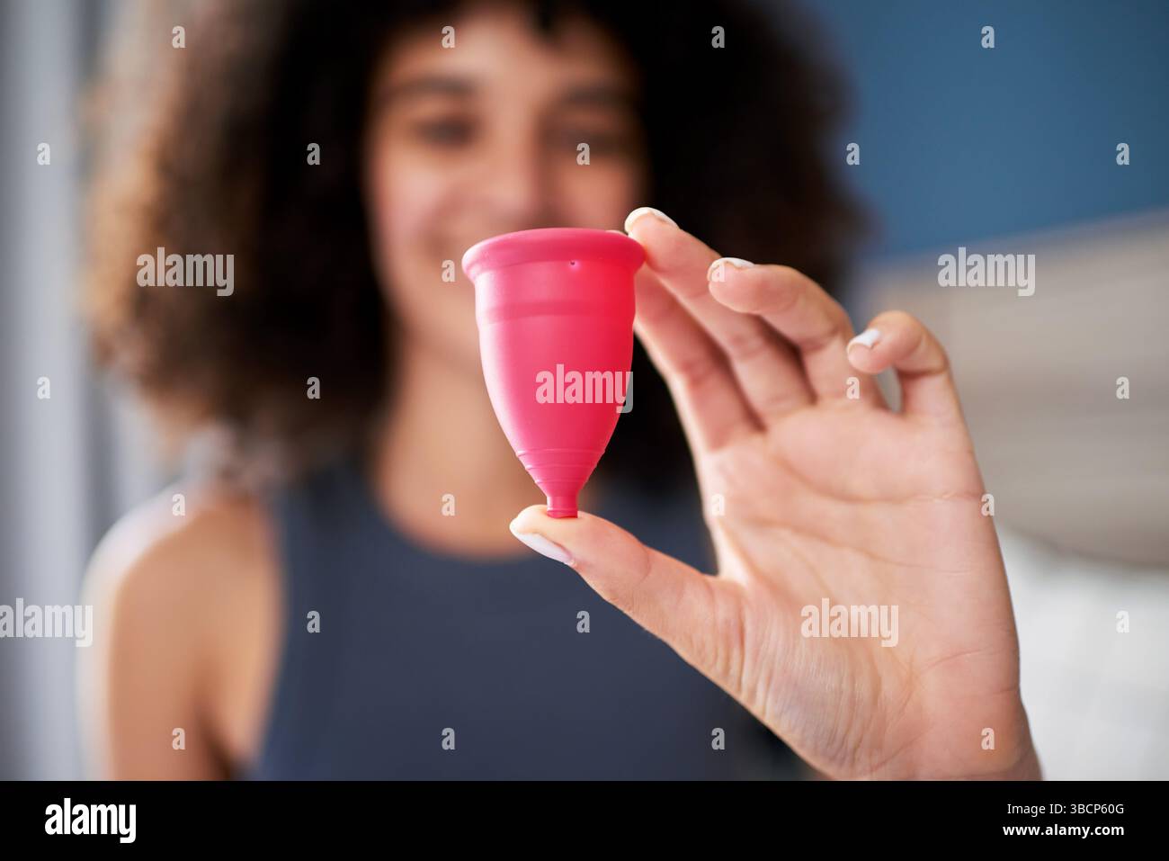 A Woman Holding a Pink Menstrual Cup in a Bright Indoor Setting, Highlighting Feminine Health and Sustainable Lifestyle Stock Photo