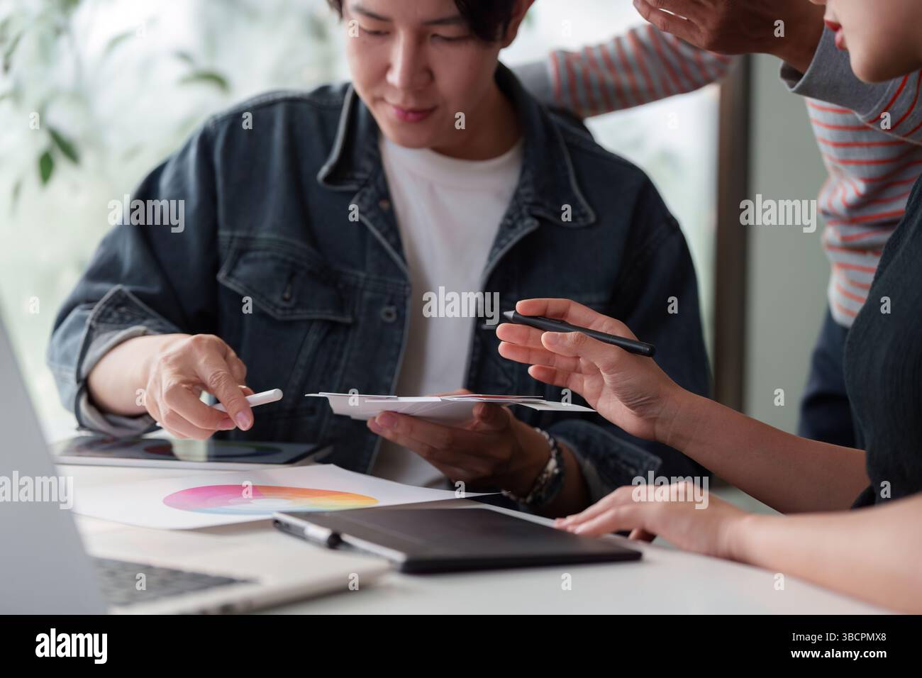Collaborative Creativity and Visual Design. An interactive team session focused on UX UI with digital devices and lively discussion. Stock Photo