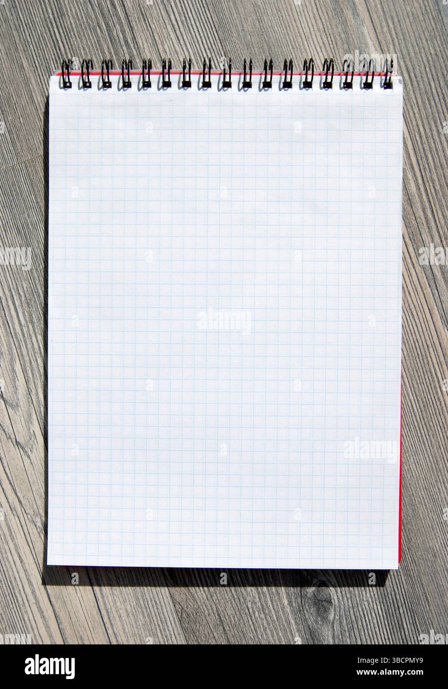 A blank notebook on a wooden background. A checked blank note page for a copy. Stock Photo