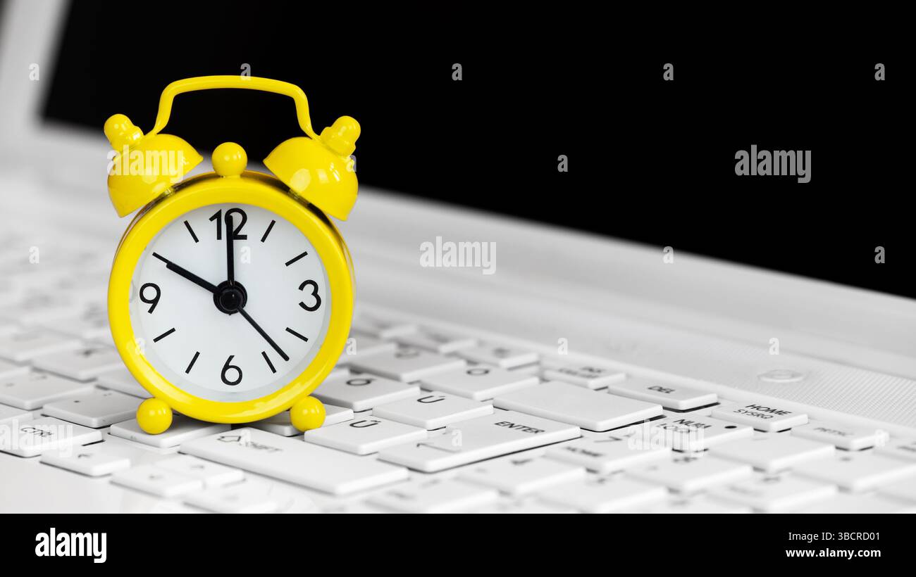 Alarm clock on a laptop keyboard, deadline concept. Background with copy space. Stock Photo