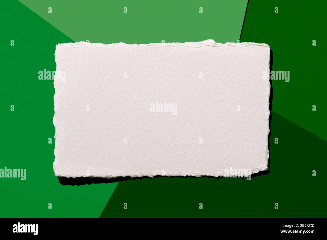 Torn white paper on green background Stock Photo