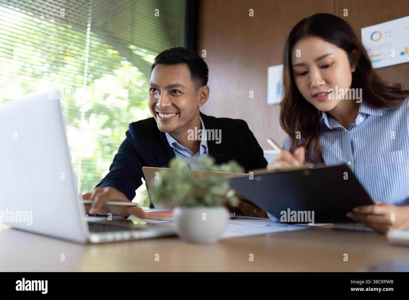 Collaborative Work Environment. Team members smiling while discussing project details on a laptop. Stock Photo