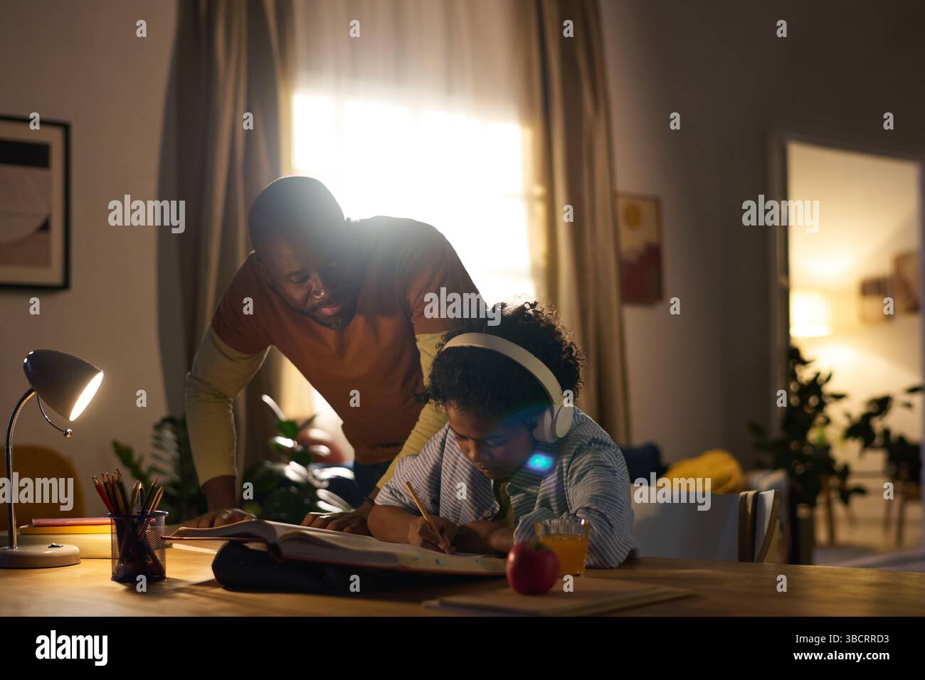 Assisting Child with Homework in Cozy Home Environment Stock Photo