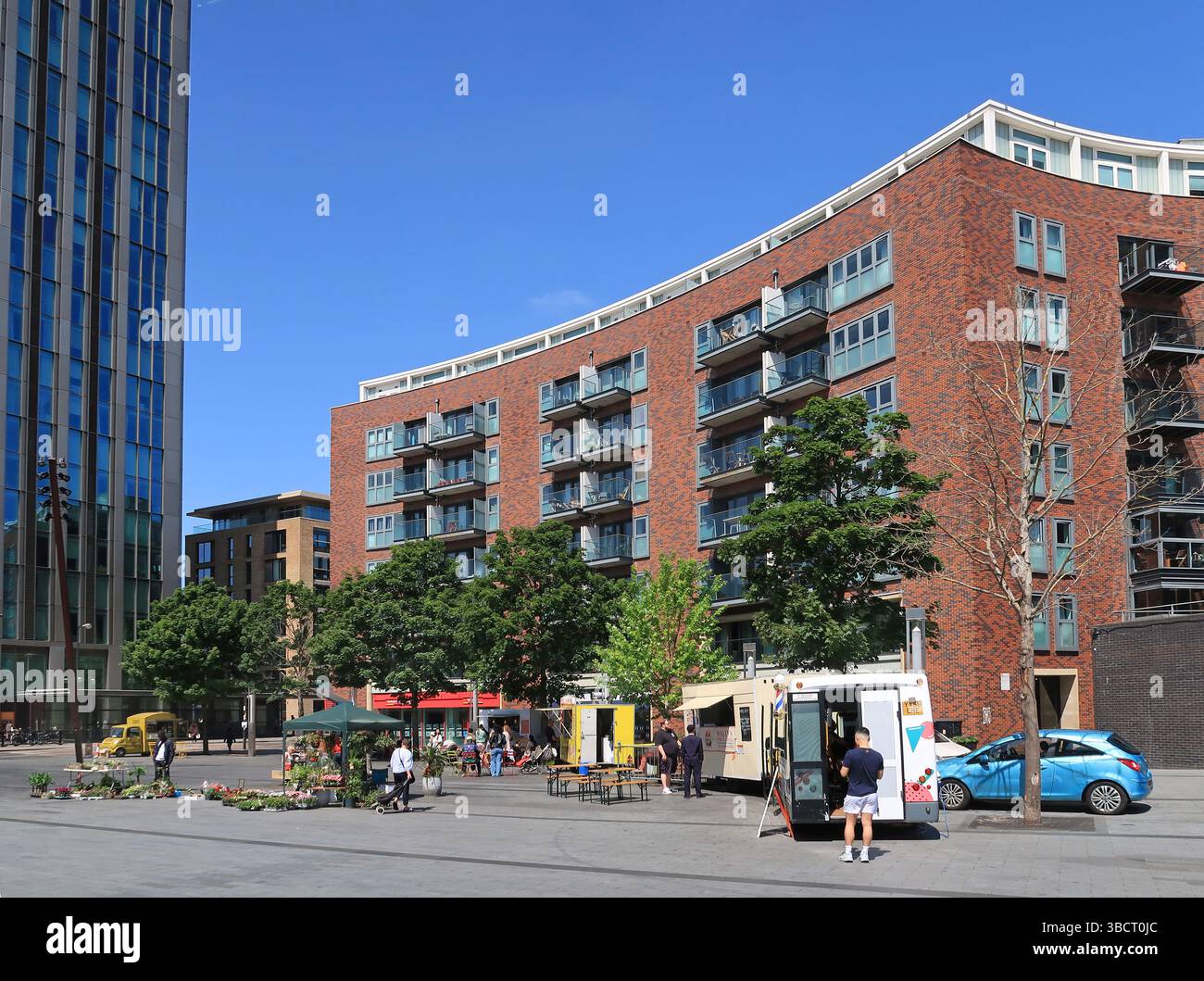 Deal Porter Square, public pedestrianised area at Canada Water in southeast London, UK. Shows seating and food stalls on a busy, spring lunchtime. Stock Photo