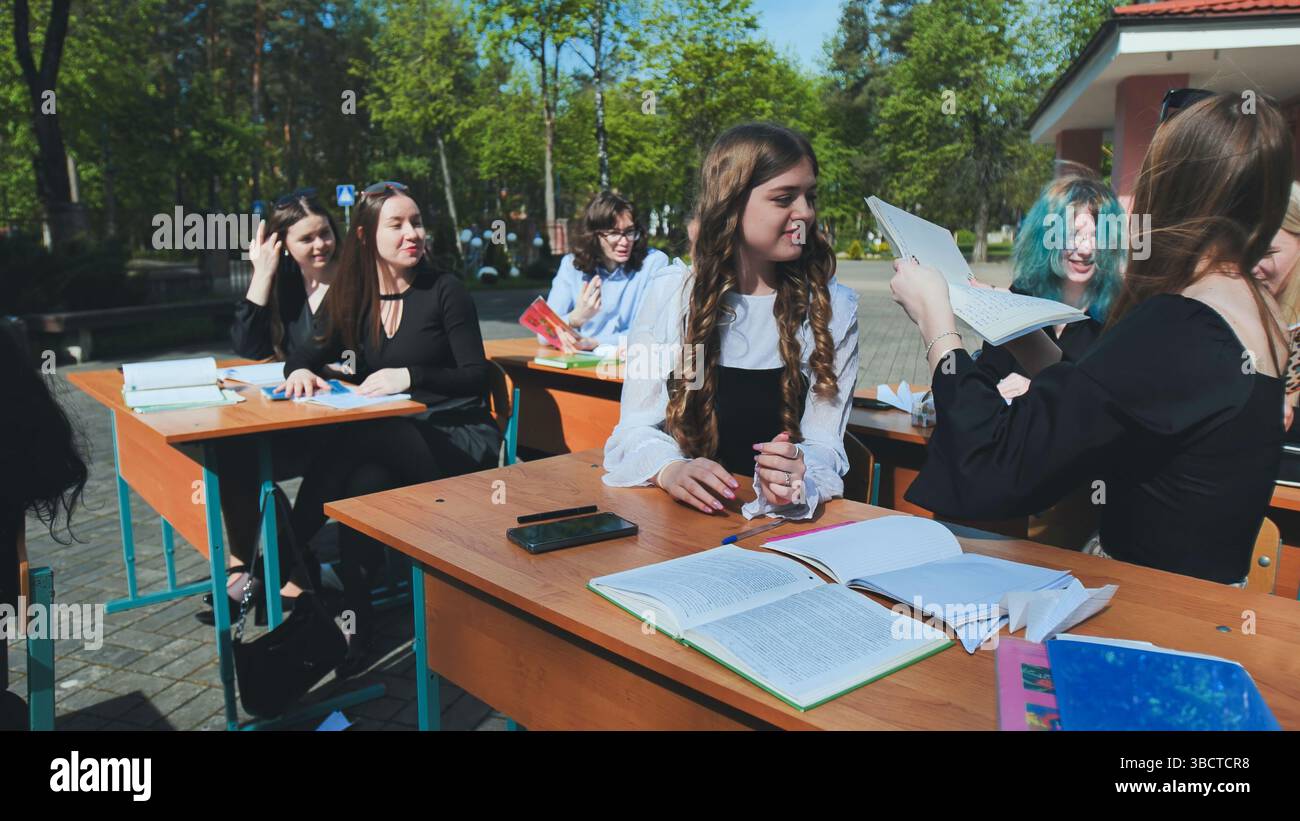 Students from high school and university are collaborating outdoors, exchanging notes and appreciating the outdoors Stock Photo