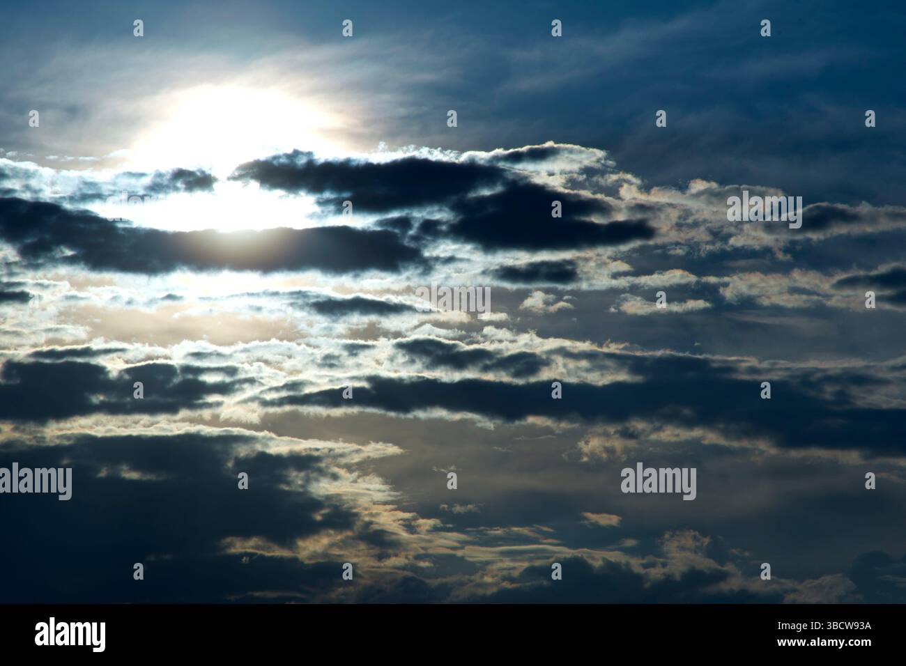 Sun pierces dramatic evening cloud layers. Stock Photo