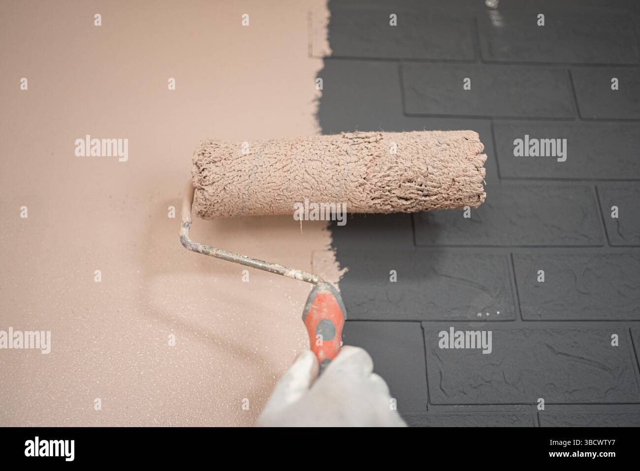 Person Using Roller to Paint Wall Stock Photo