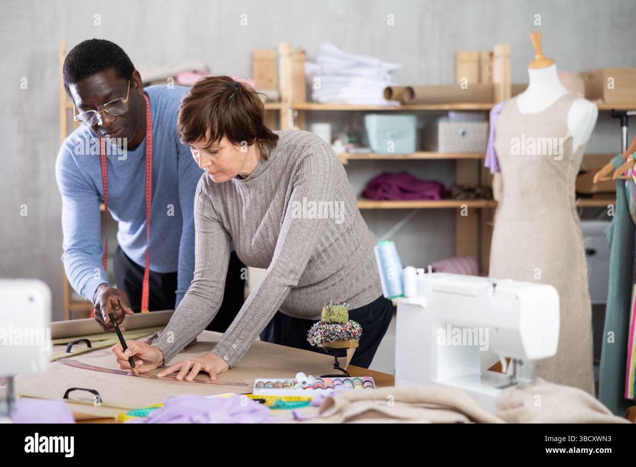 Two sewing workshop workers draw patterns on paper Stock Photo