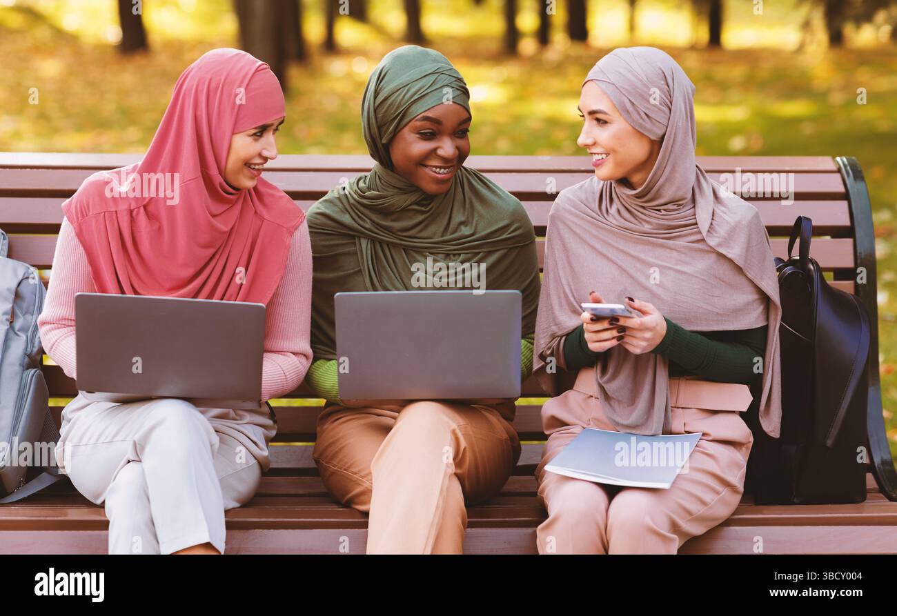 Muslim Female Students Using Laptops And Smartphone Learning Together Outside Stock Photo