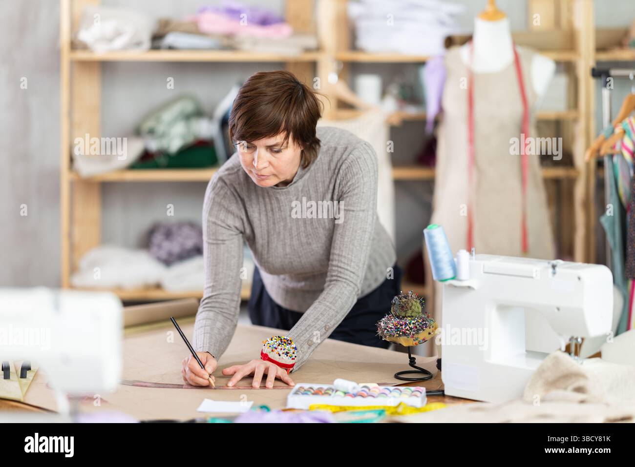 Female dressmaker draws sketch of future clothing on paper using ...
