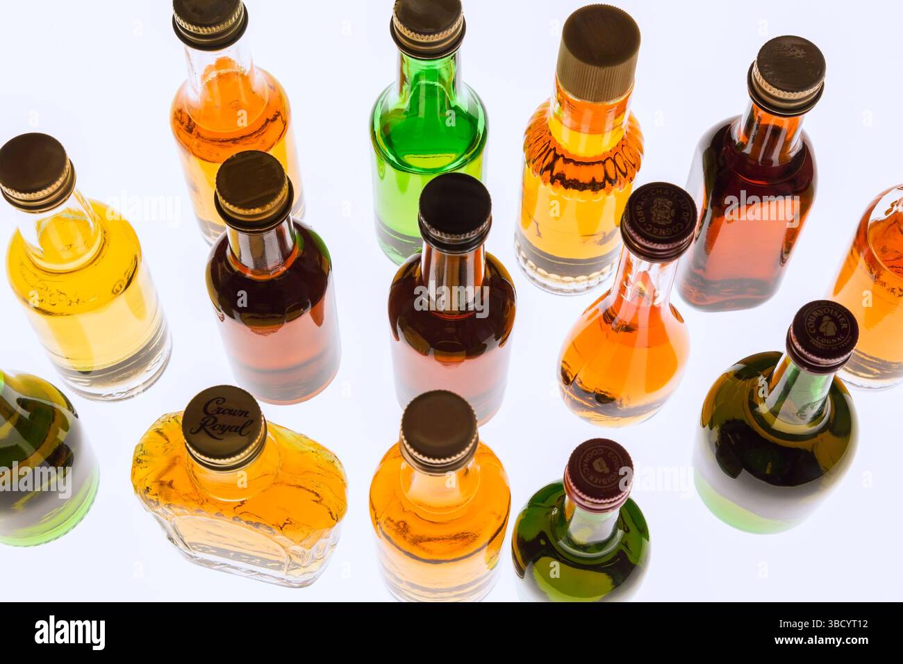 Colourful assorted shaped miniature size liquor bottles on white translucent background. Stock Photo
