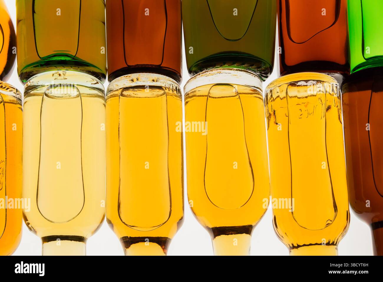 Two rows of colourful assorted shaped miniature size liquor bottles laid flat on white translucent background. Stock Photo
