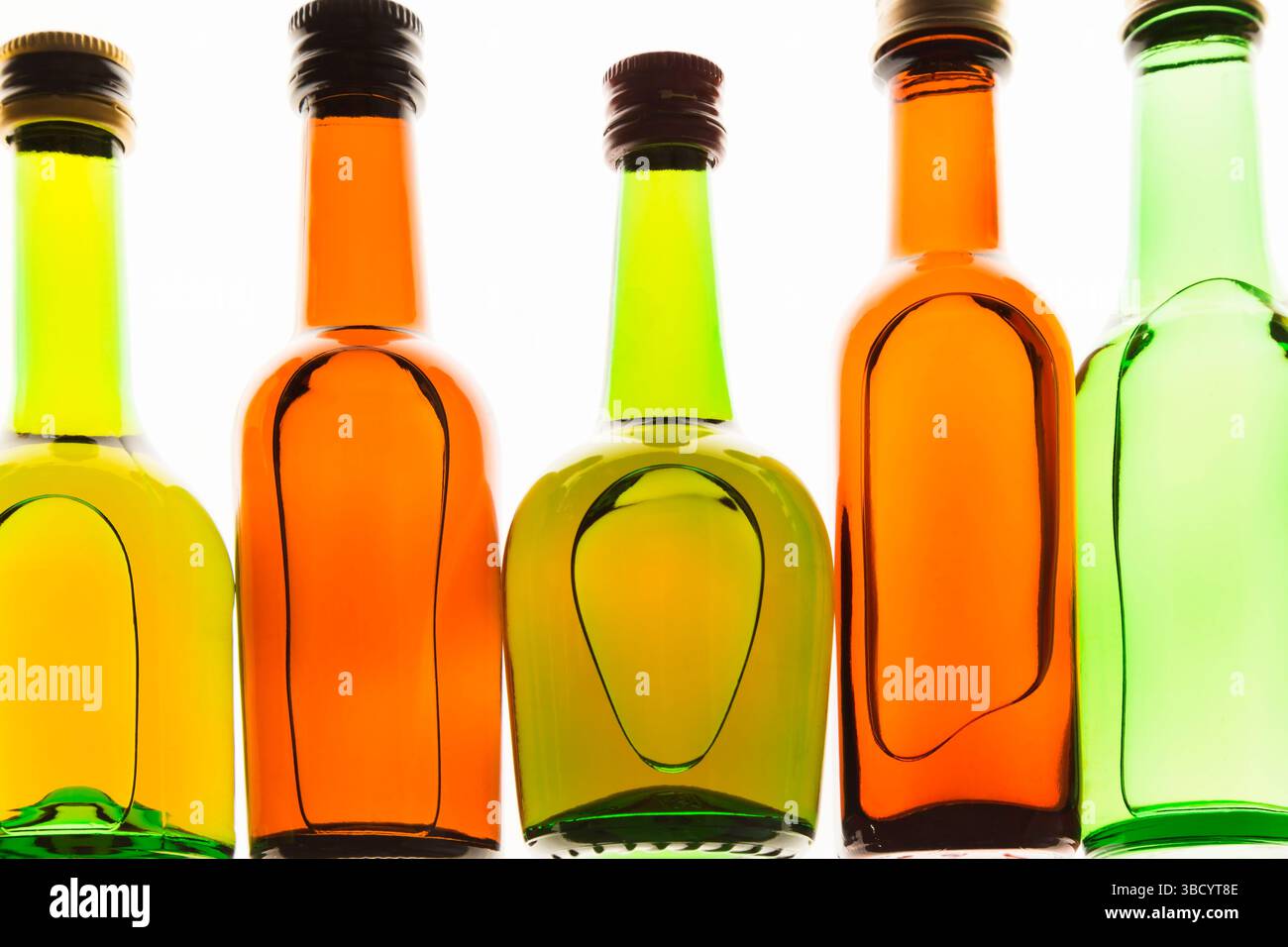 Colourful assorted shaped upright miniature size liquor bottles on white translucent background. Stock Photo