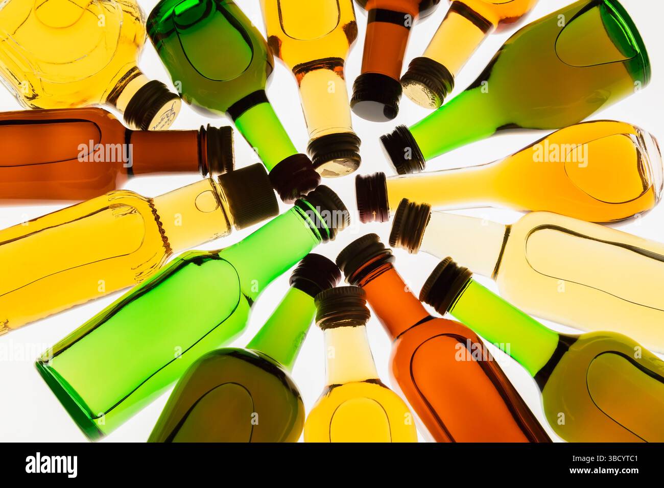 Colourful assorted shaped miniature size liquor bottles laid flat in circular design on white translucent background. Stock Photo