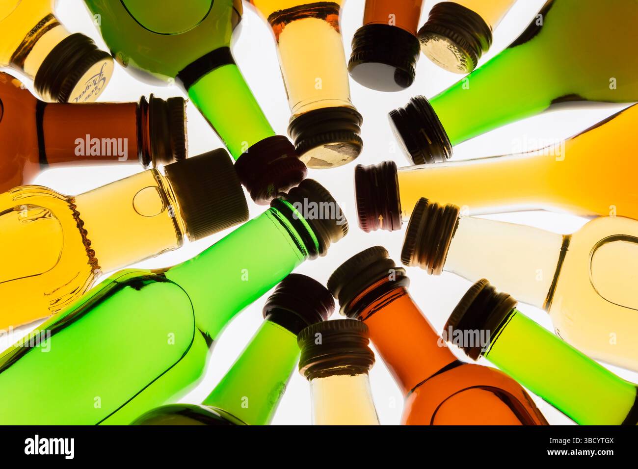 Colourful assorted shaped miniature size liquor bottles laid flat in circular design on white translucent background. Stock Photo