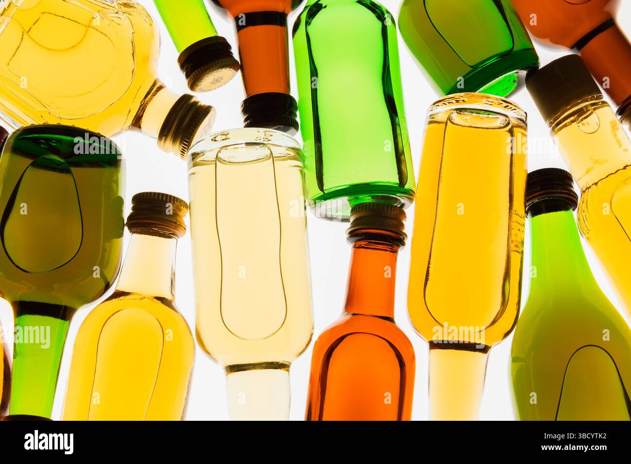 Colourful assorted shaped miniature size liquor bottles laid flat on white translucent background. Stock Photo