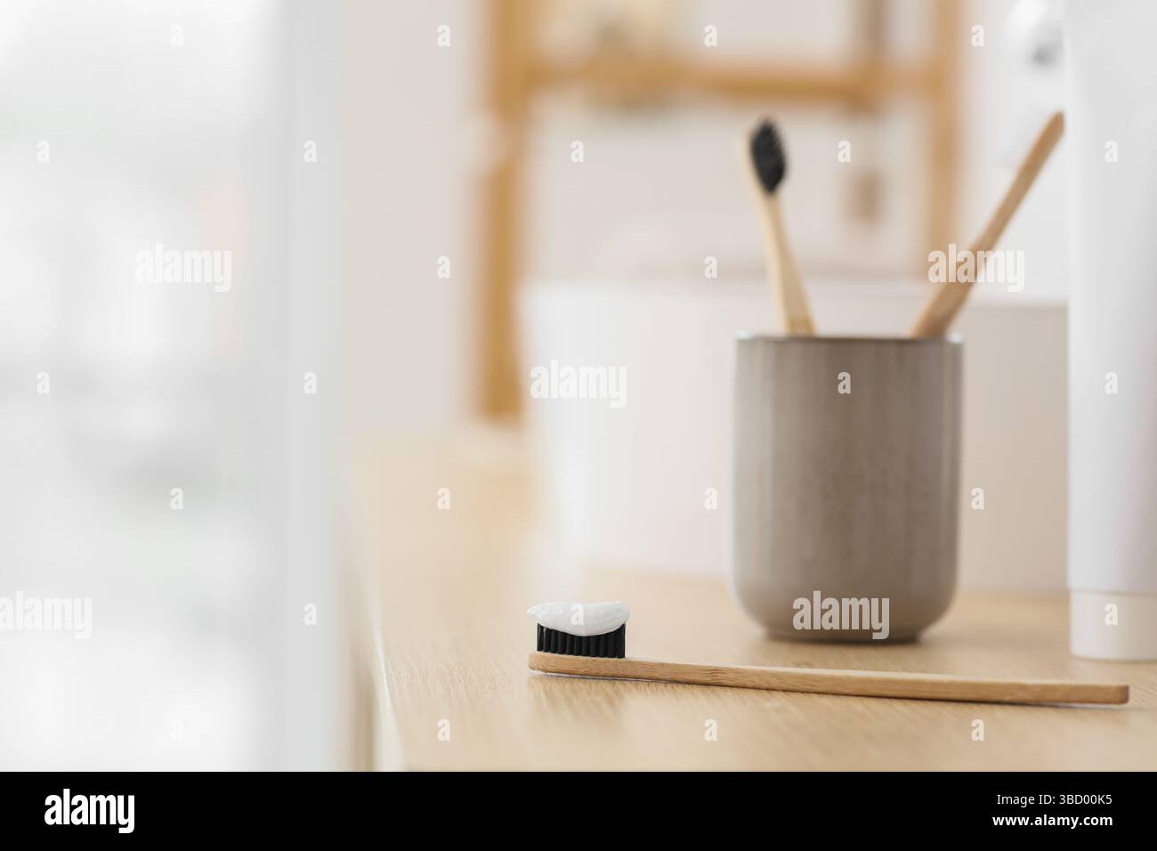 Bamboo tooth brush with applied tooth paste on table in bathroom Stock Photo